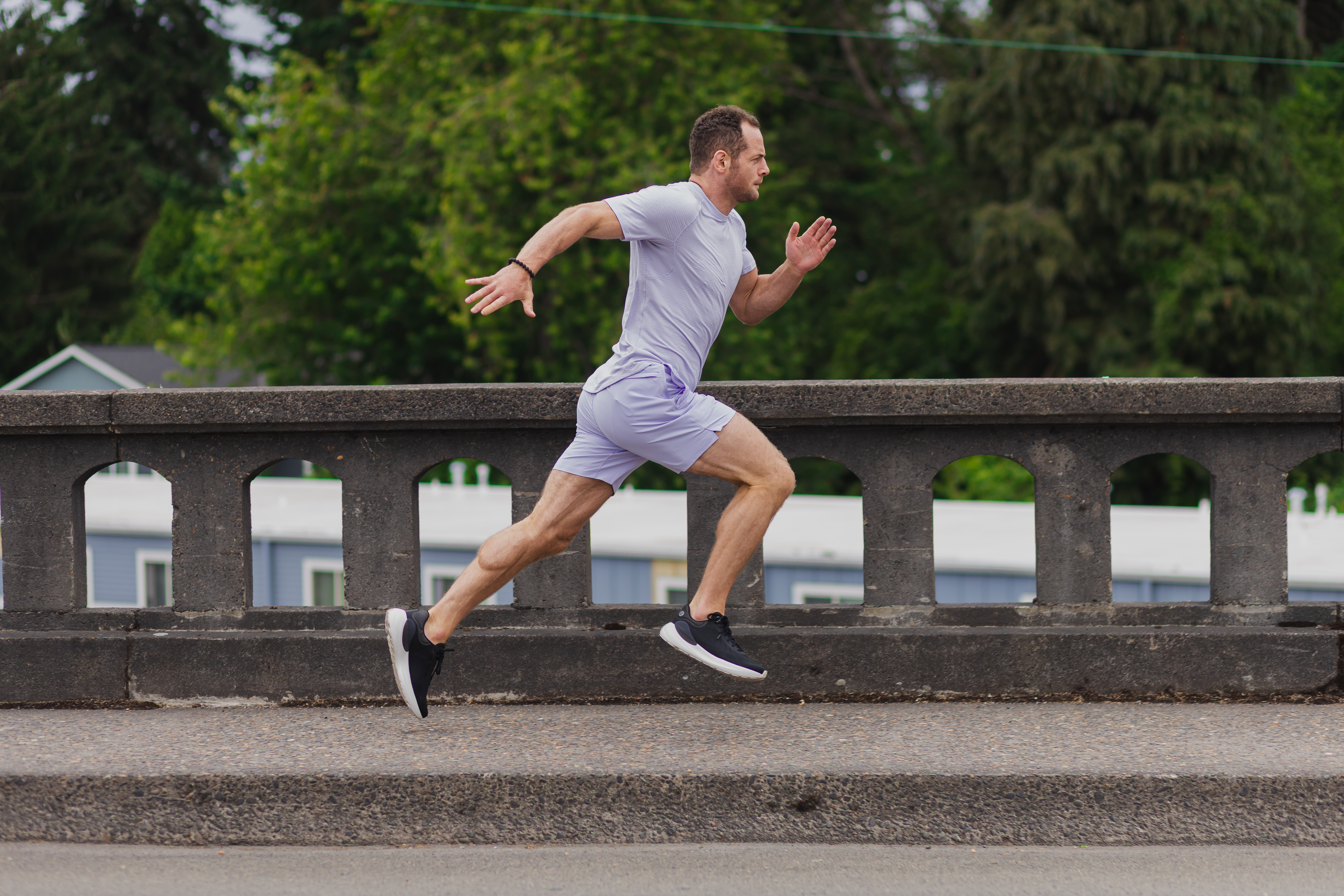 Man running on a bridge with trees in the background.