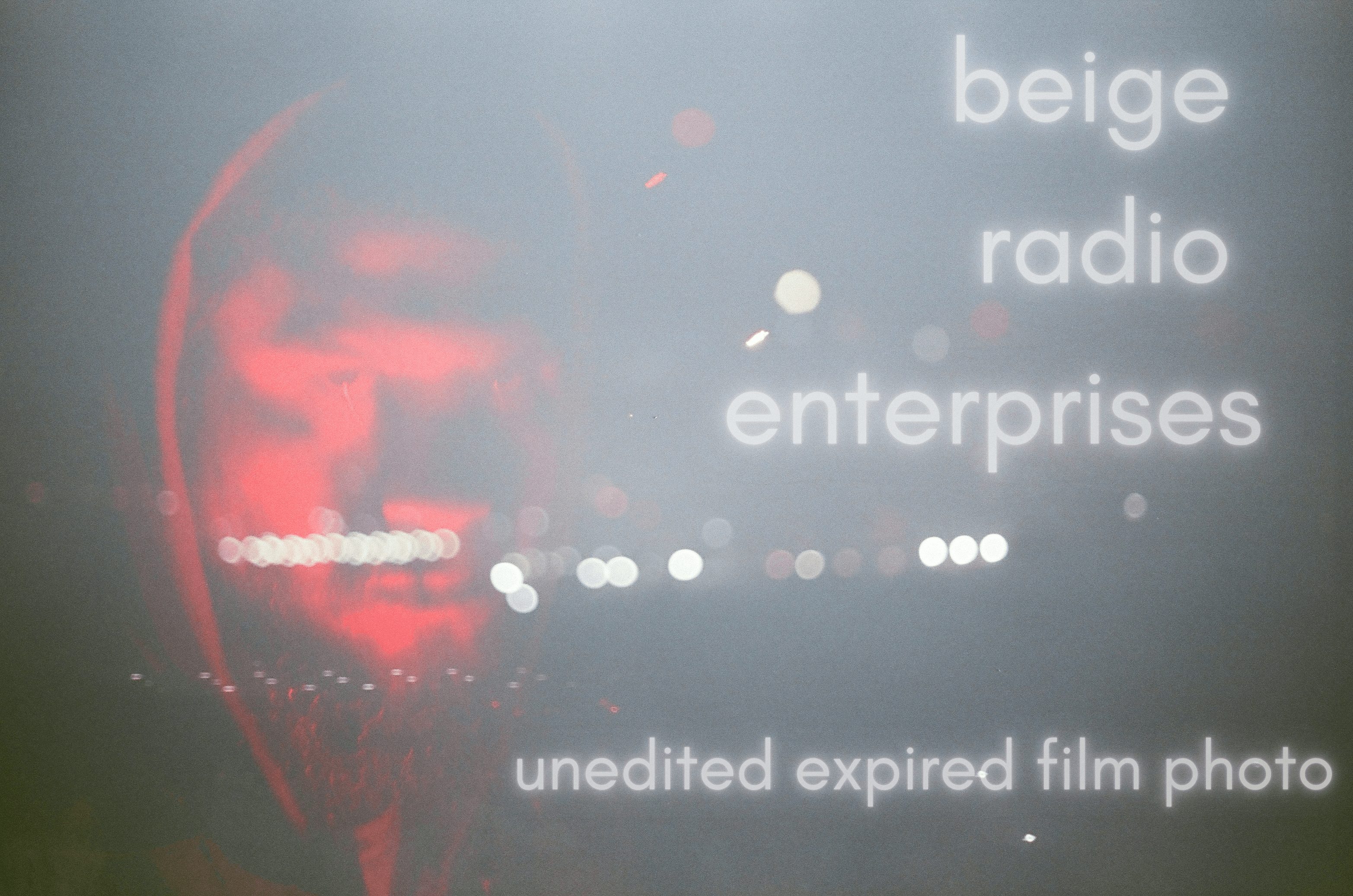 Text on screen reads 'beige radio enterprises' and 'unedited expired film photo' with blurred lights in background.