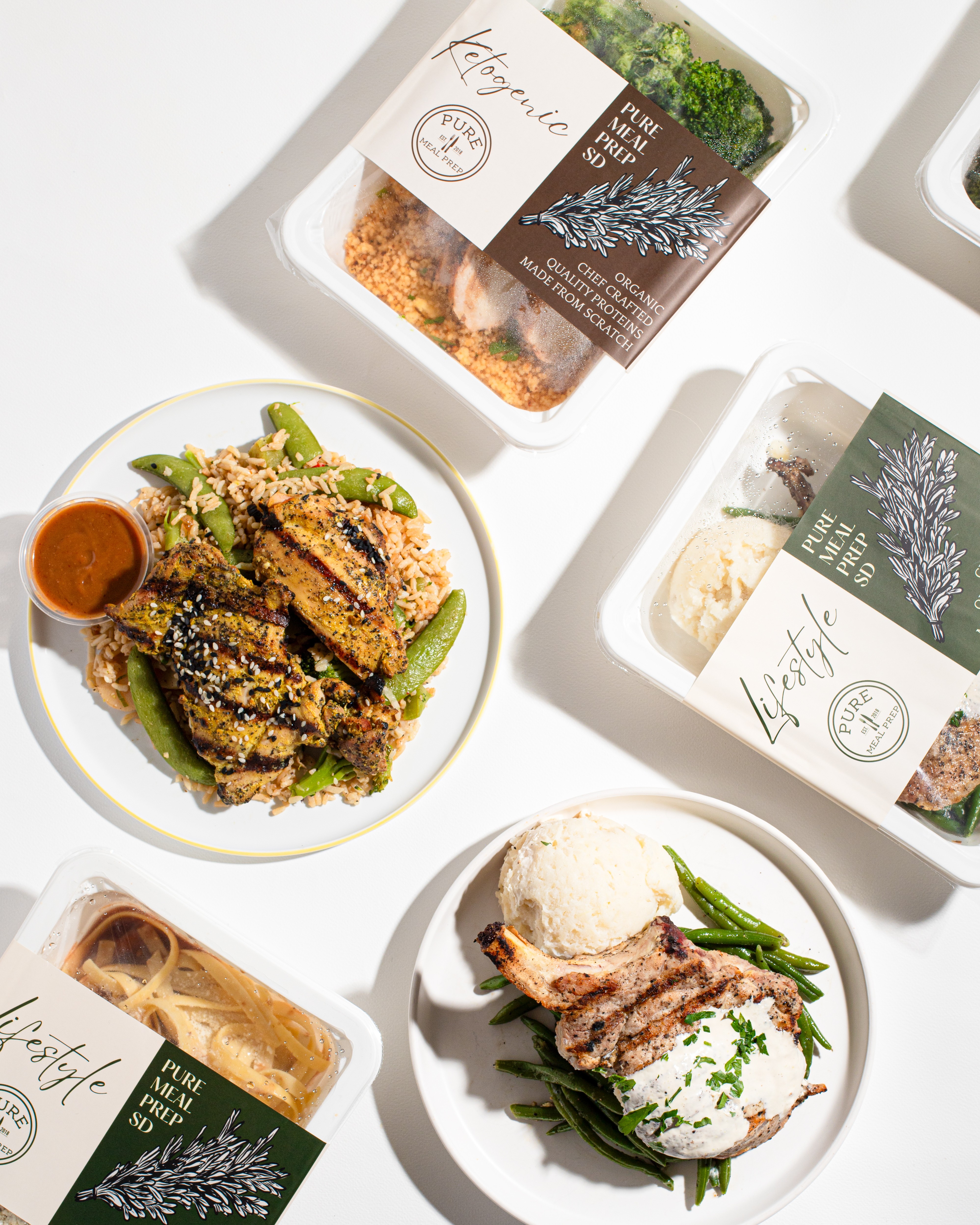 Two plates of food, one with fried chicken, green beans, and dipping sauce, and the other with a sandwich and a scoop of ice cream, on a white surface.