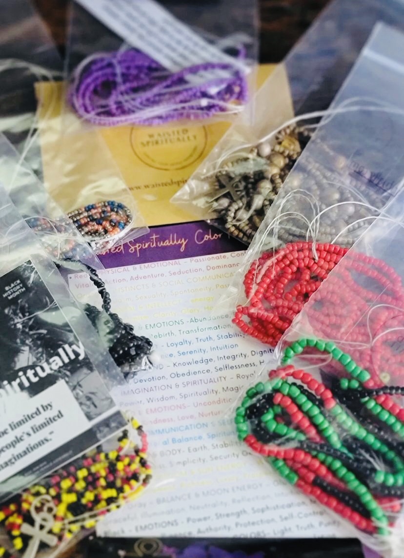 Various colorful beaded jewelry and accessories displayed on a table with papers and packaging.