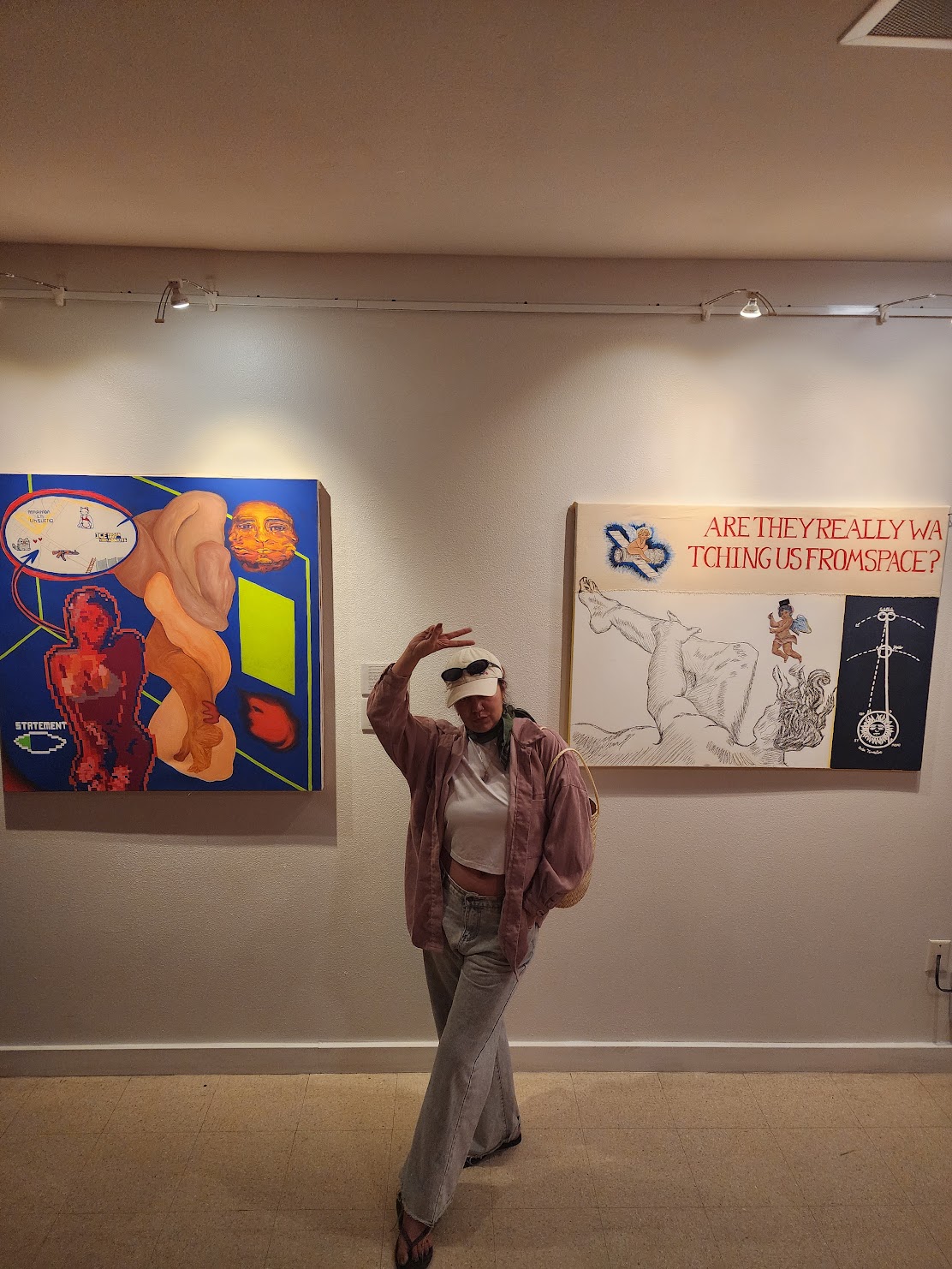 Person standing in front of two colorful paintings on a wall, wearing sunglasses, a jacket, and wide-leg pants.