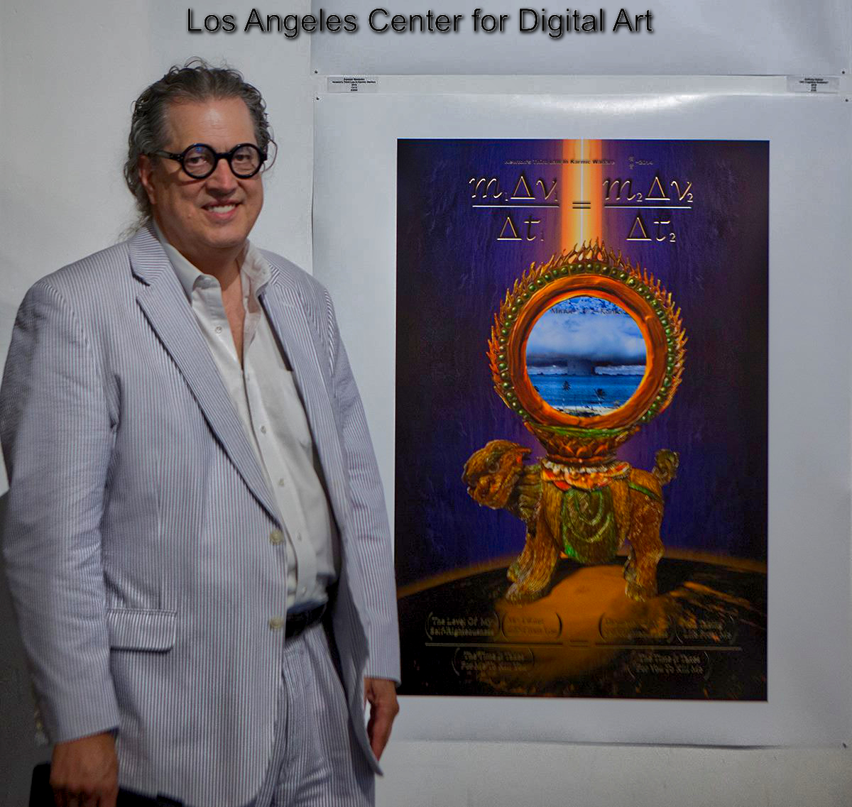 Person in light-colored suit and glasses standing next to digital art poster at Los Angeles Center for Digital Art.