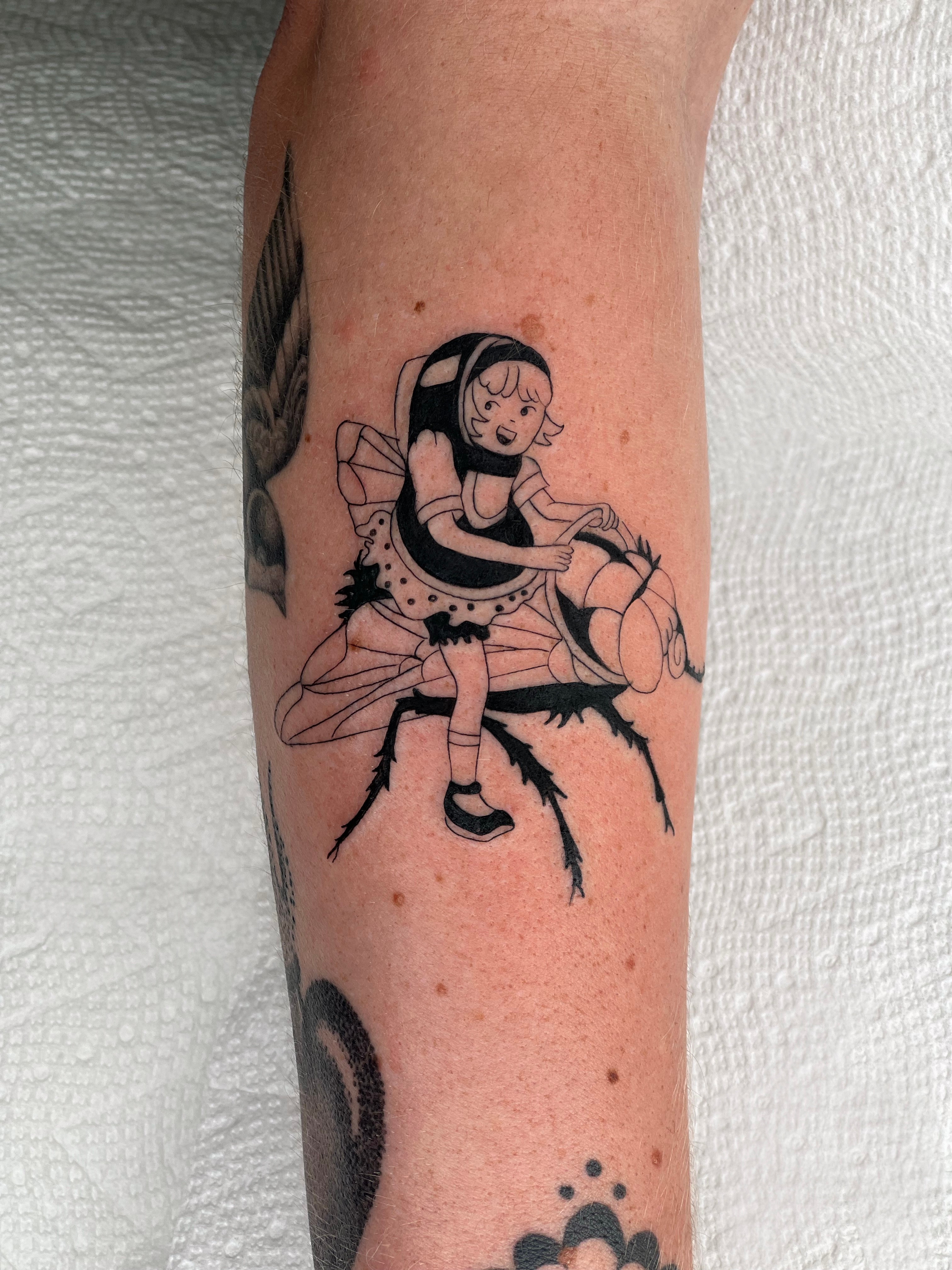 Tattoo of a girl with long hair sitting on a branch, holding a basketball, with a neutral background.