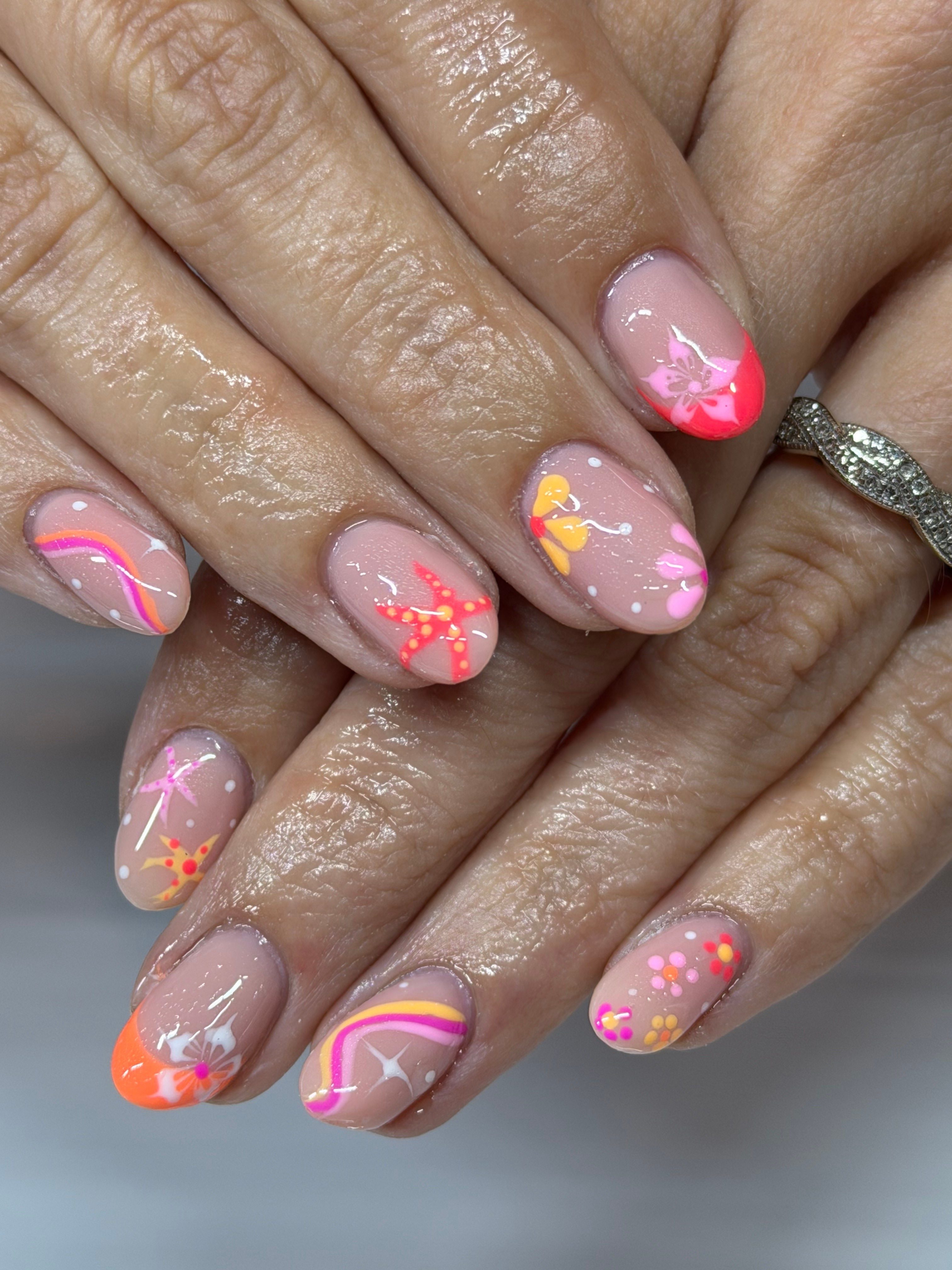 Close-up of hands with colorful floral and abstract nail art on natural nails, some with pink, orange, yellow, and purple designs.