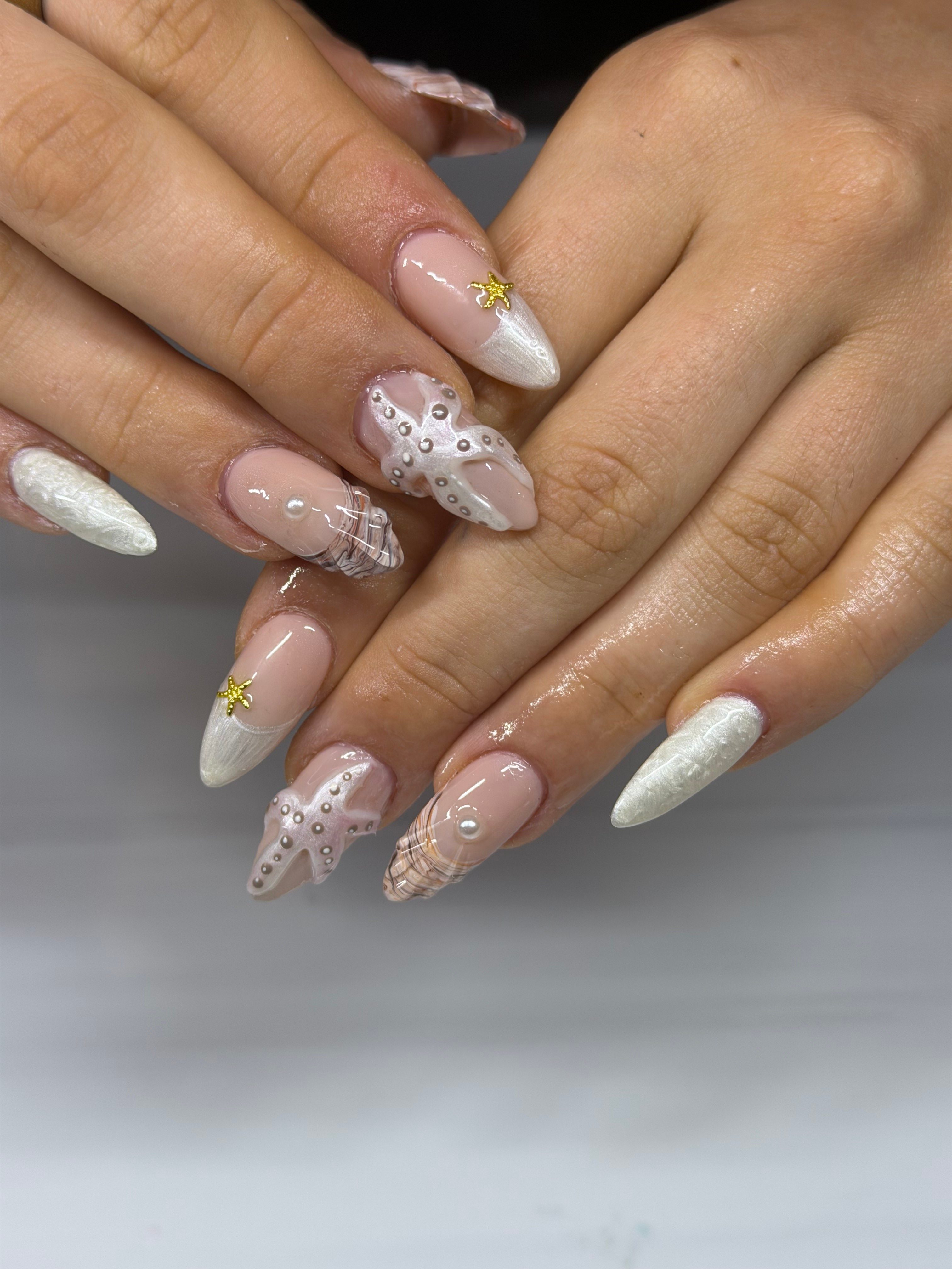 Close-up of hands with decorated nails, featuring white, pink, and gold accents, and floral designs.