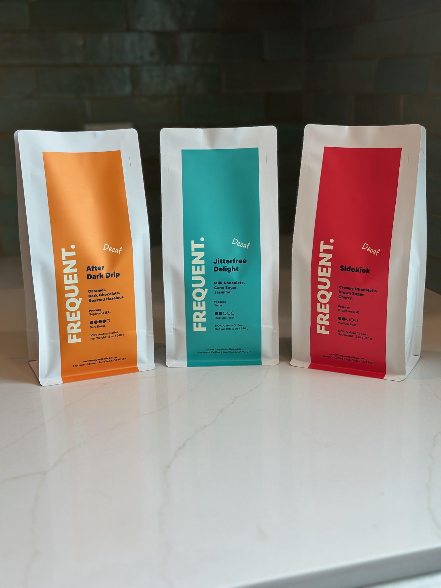 Three standing packages with colorful labels on a white surface, dark background, front view.