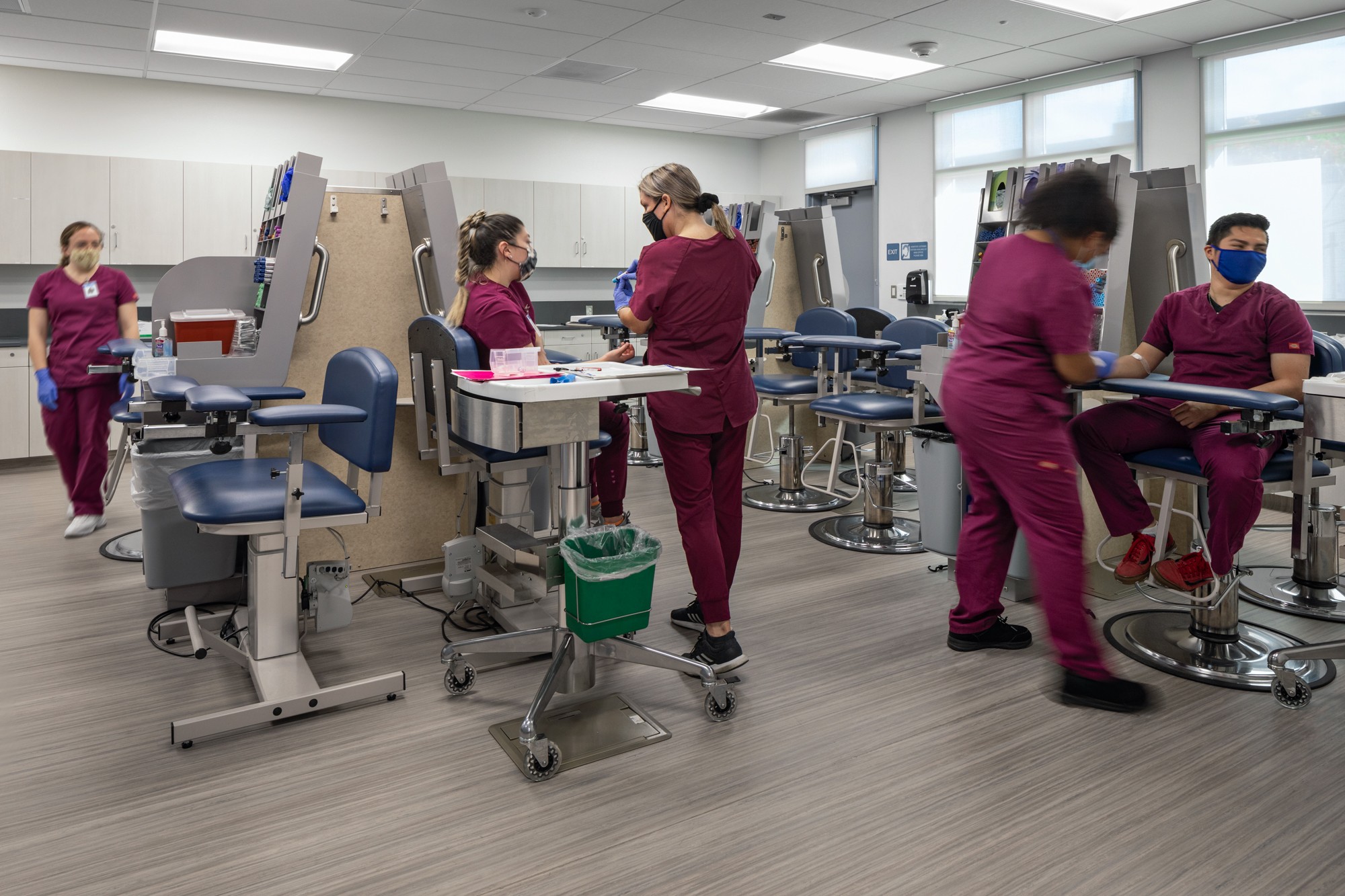 Medical training room with healthcare students practicing on simulation mannequins, wearing scrubs and masks.
