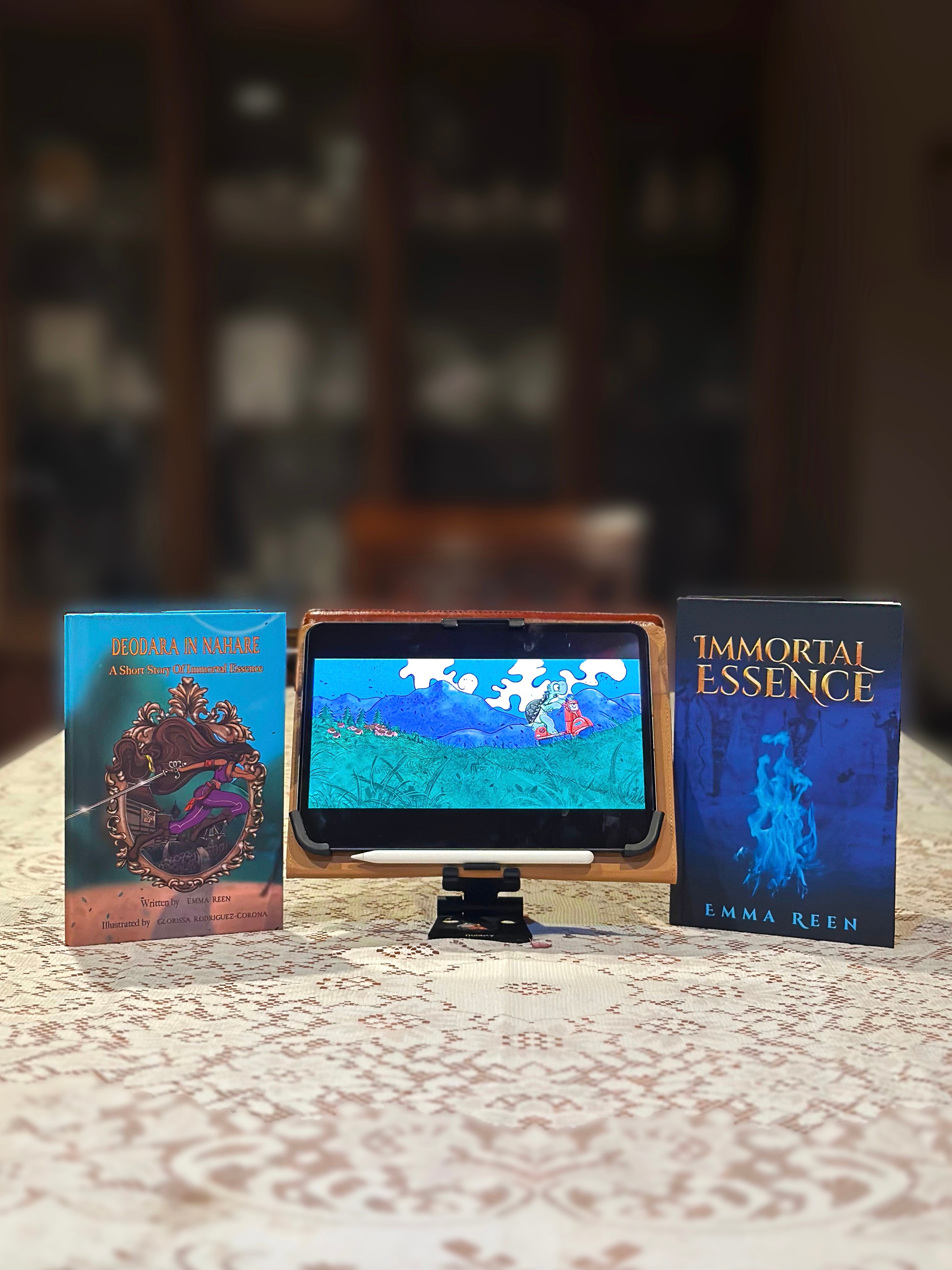 Three books and a tablet on a table, with a blurred background of a cabinet. The books are colorful and upright.