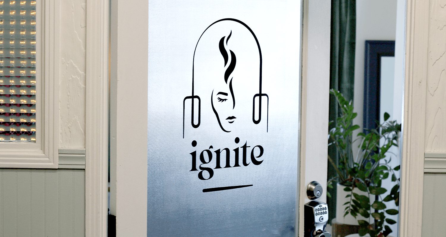 Frosted glass door with a logo of a face with headphones and the word 'ignite' below.