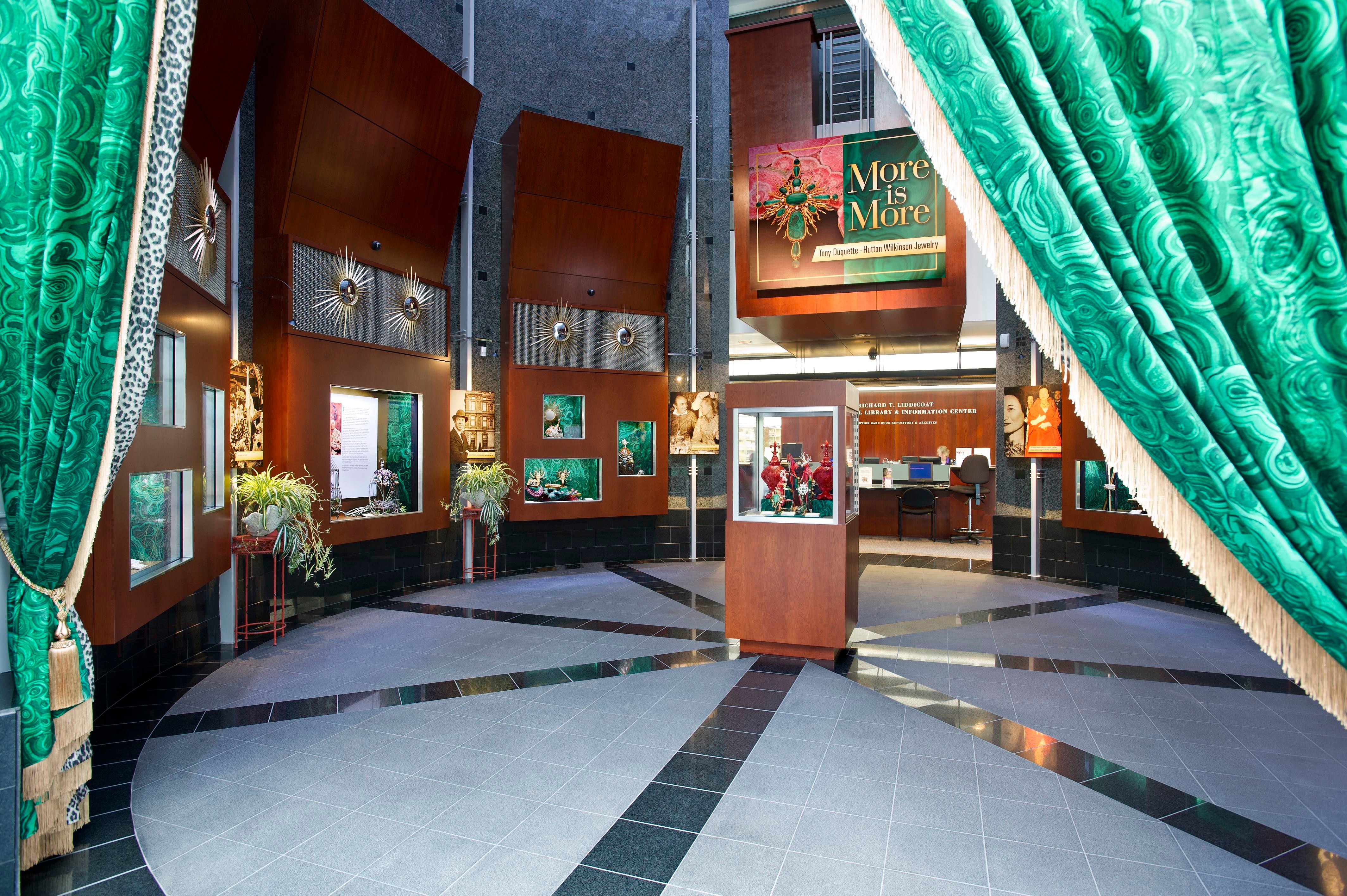 Lobby with green curtains, display cases, and a sign reading 'More to Explore,' with a tiled floor and decorative lighting.