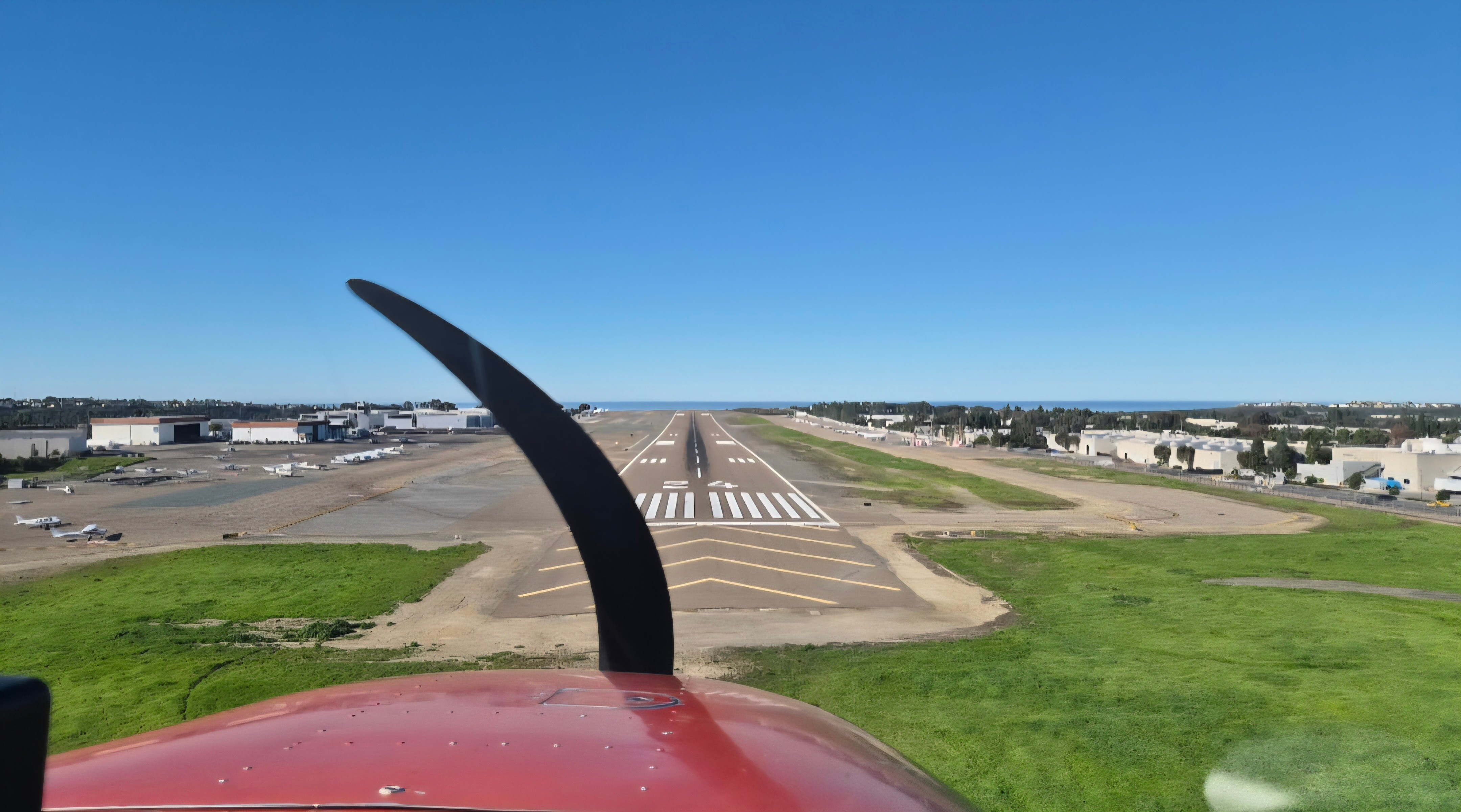 View from airplane cockpit showing runway and clear blue sky.