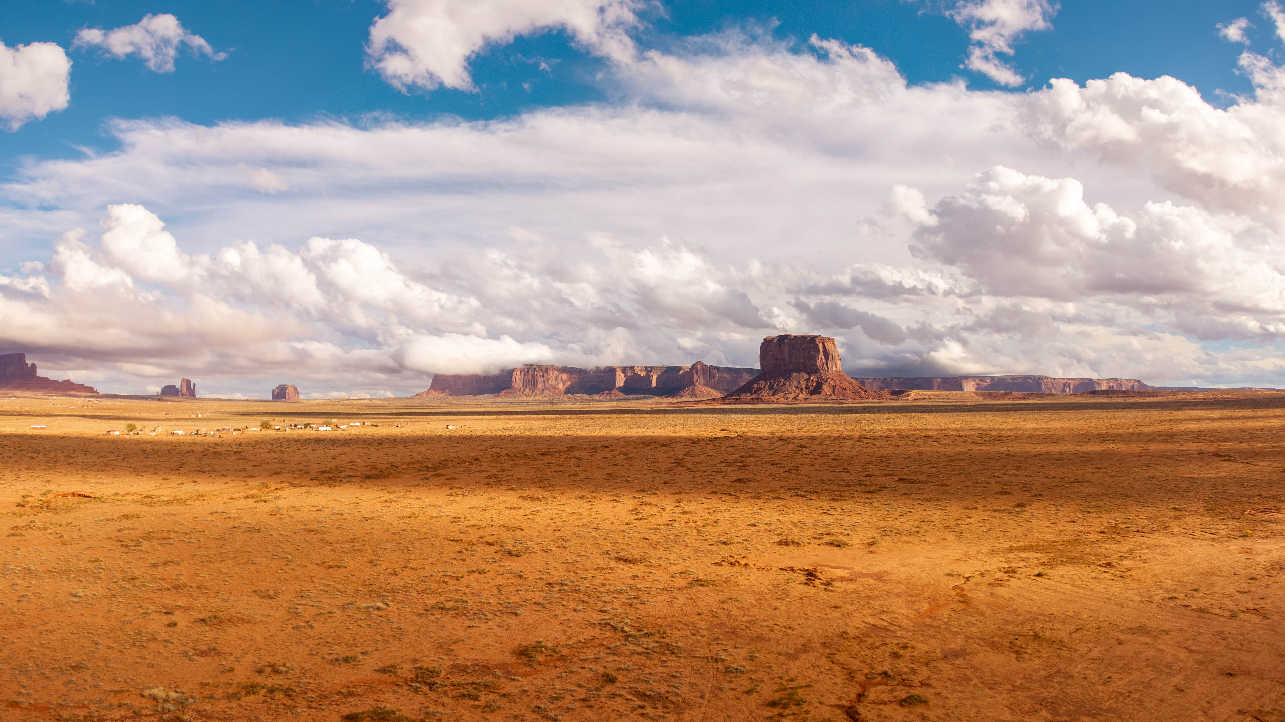 Wide desert landscape with distant mesas under a partly cloudy sky.