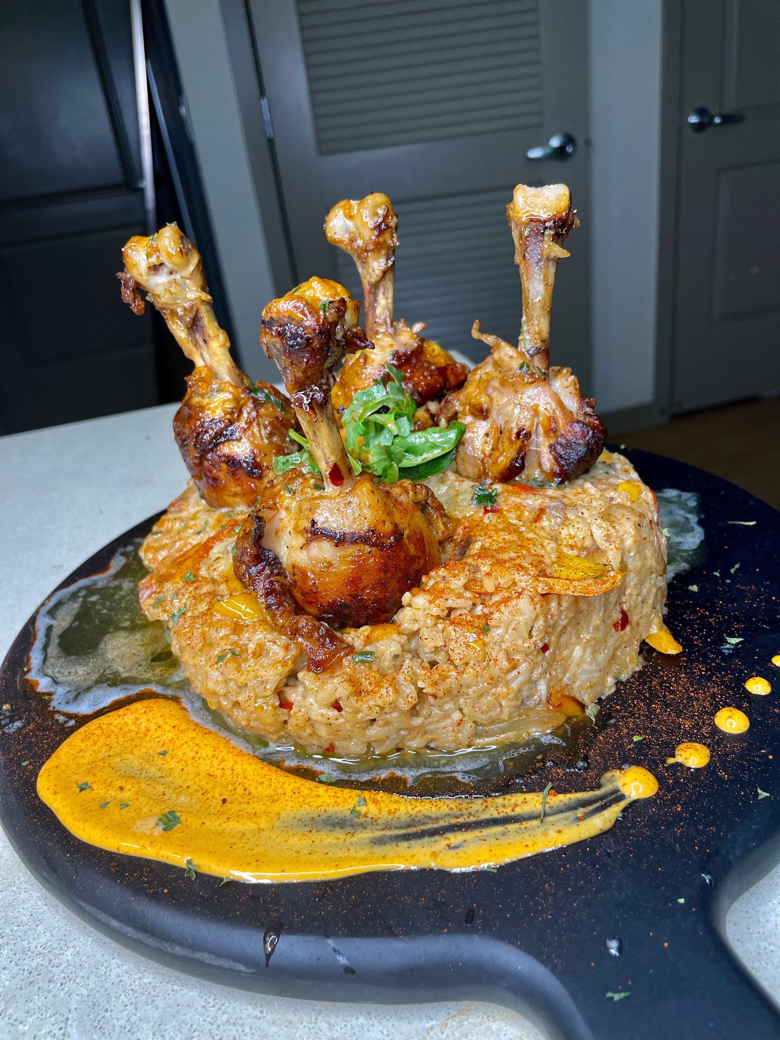 Lamb shank roast on a bed of mashed potatoes with sauce and garnished with herbs, served on a black plate.