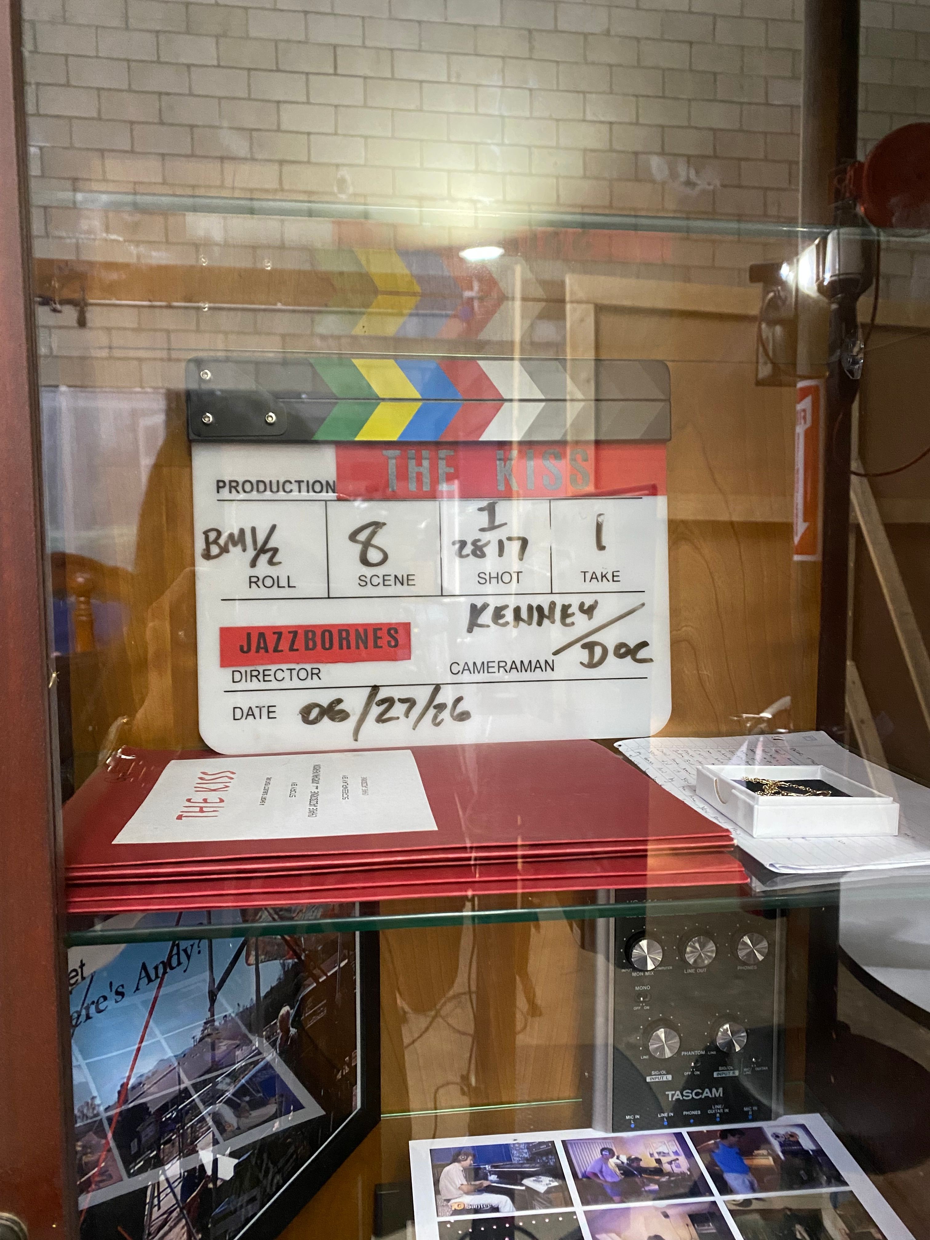 Display case with a sign, colorful objects, and a laptop, viewed from the side with reflections on glass.