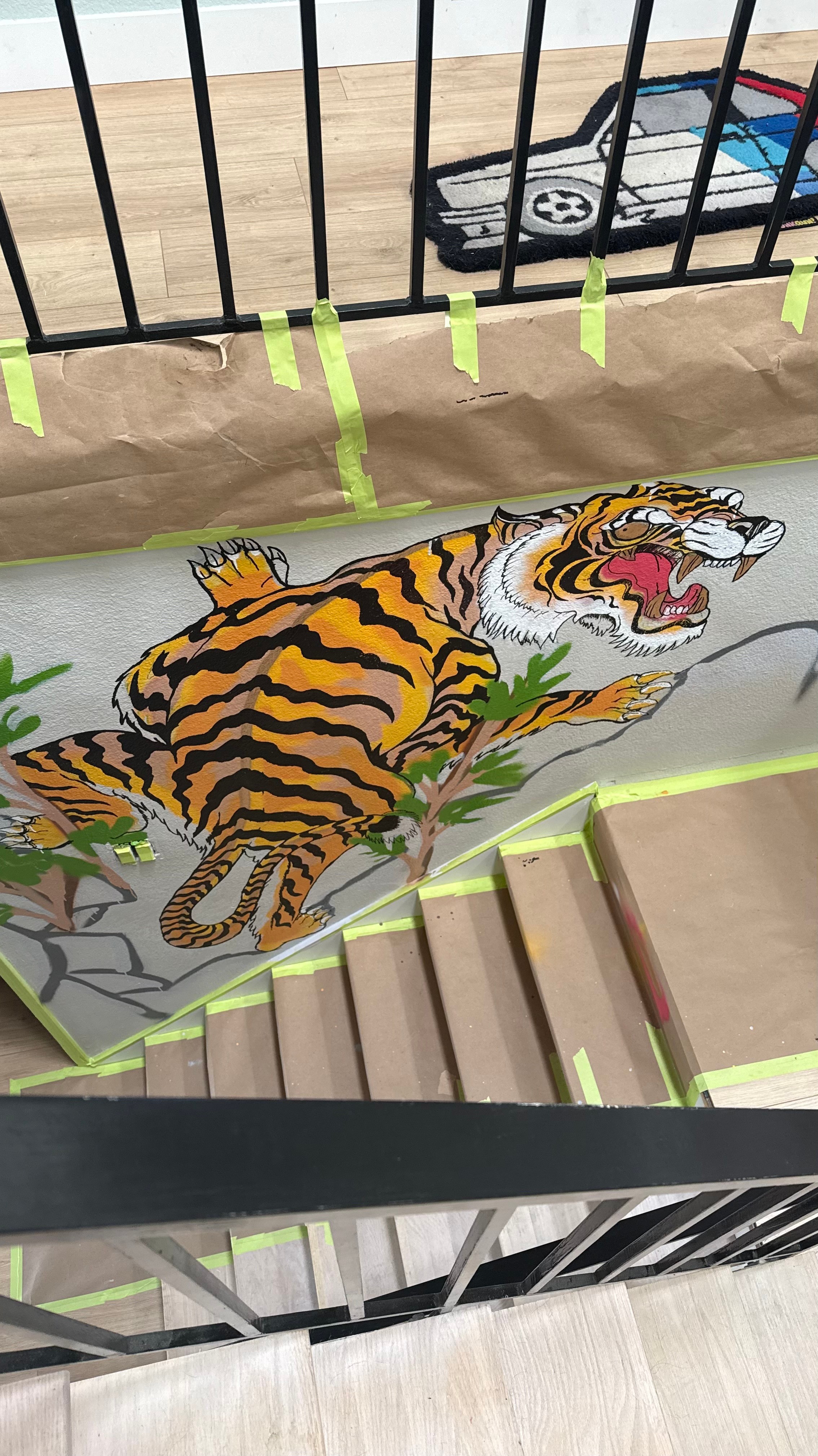 Colorful tiger illustration on paper, with black bars and a toy car in the background, on a surface with paper and a pencil.
