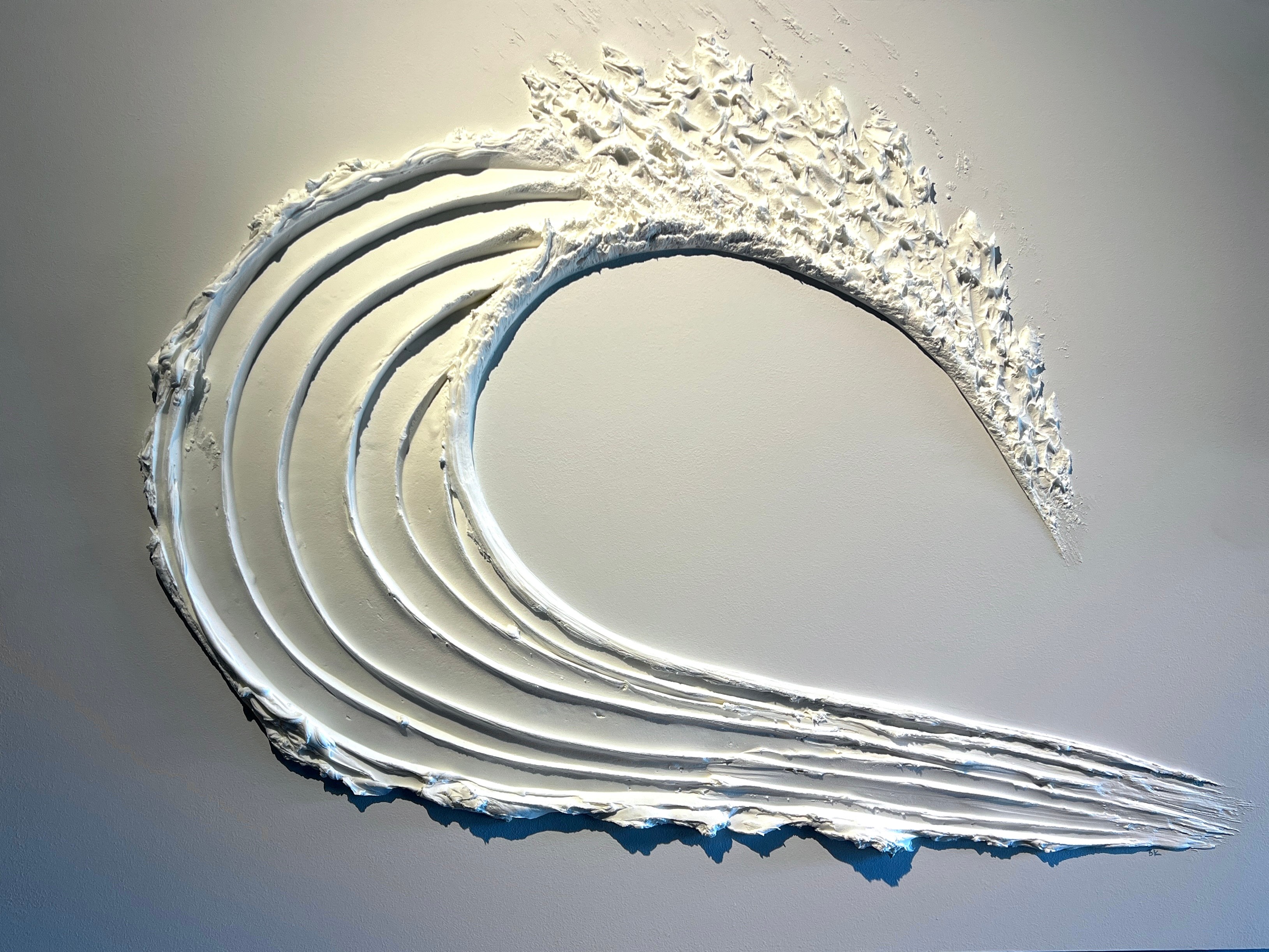 A wave-shaped sculpture with layered, textured surfaces, displayed against a plain background.