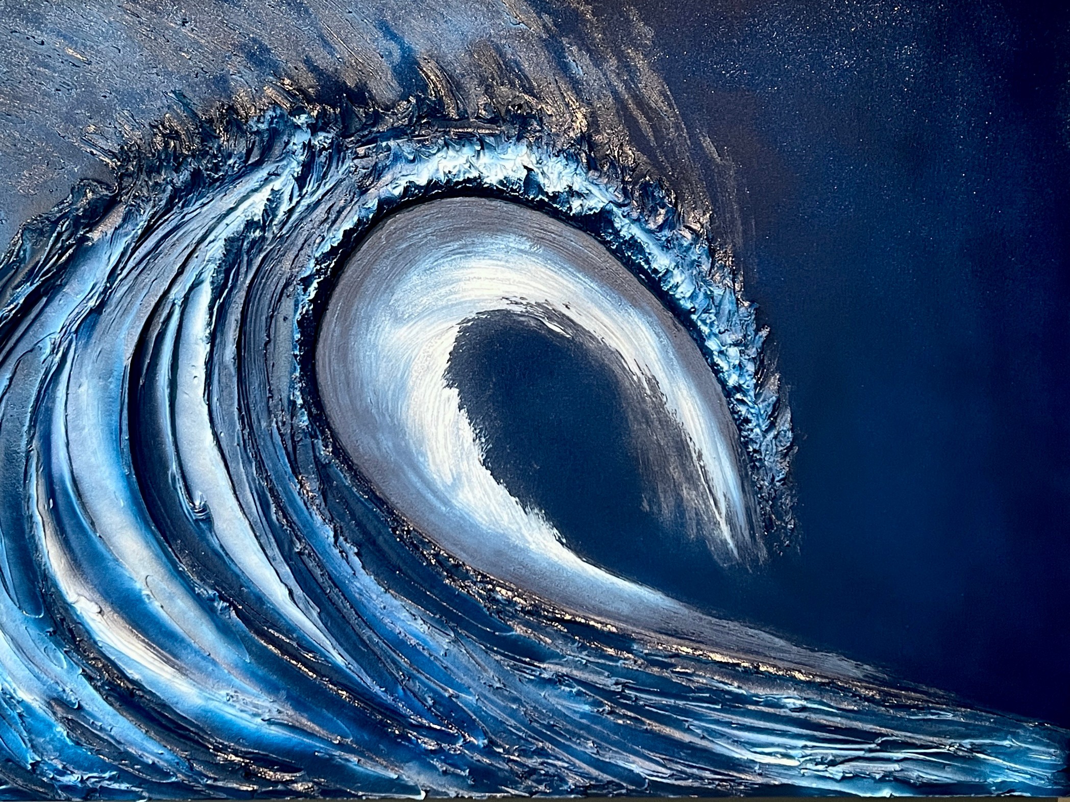 A large ocean wave curling over with white foam and deep blue water, set against a dark background.