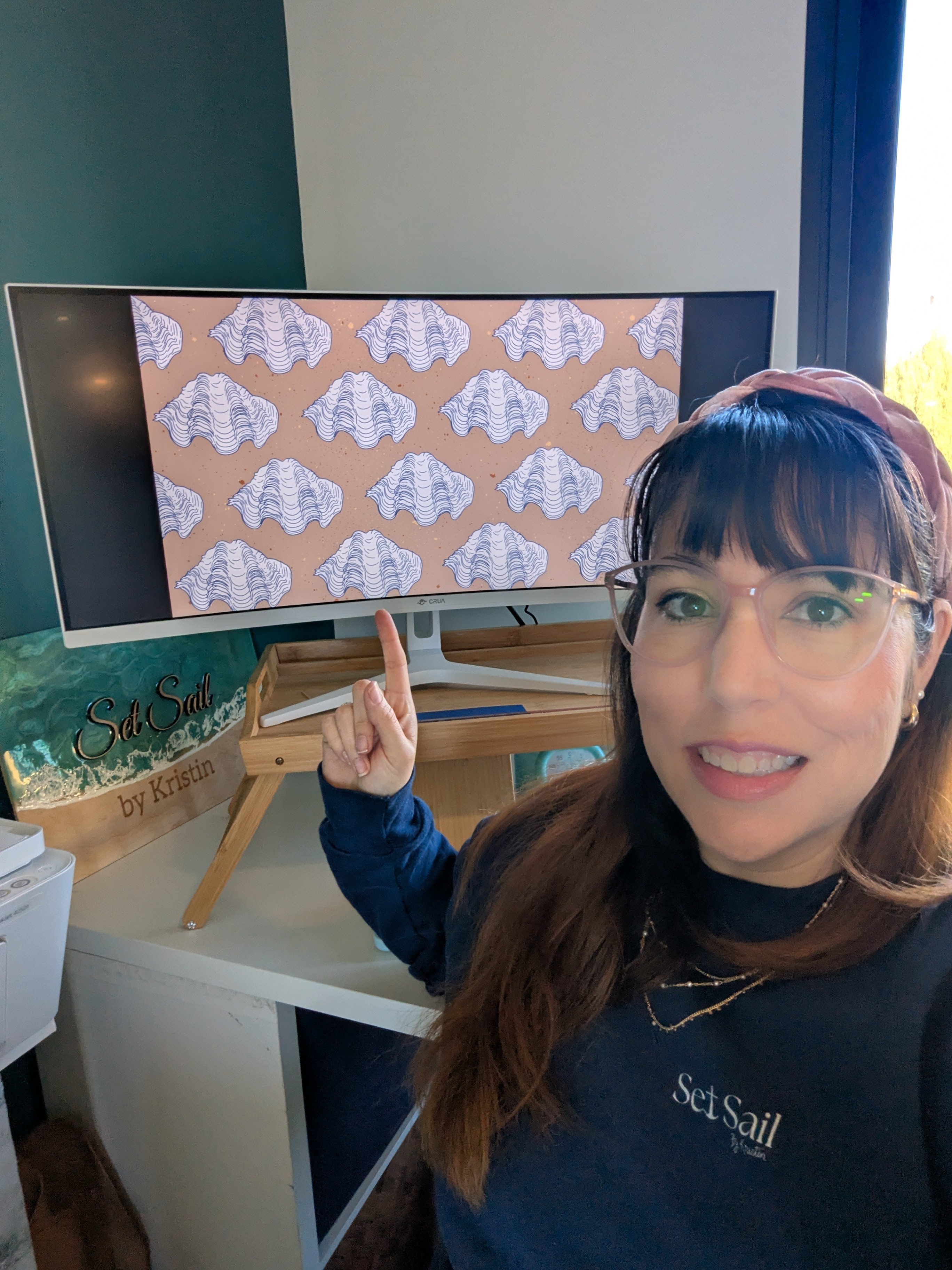 Woman with glasses and long hair points at a TV screen displaying a pattern of white elephants on a beige background.