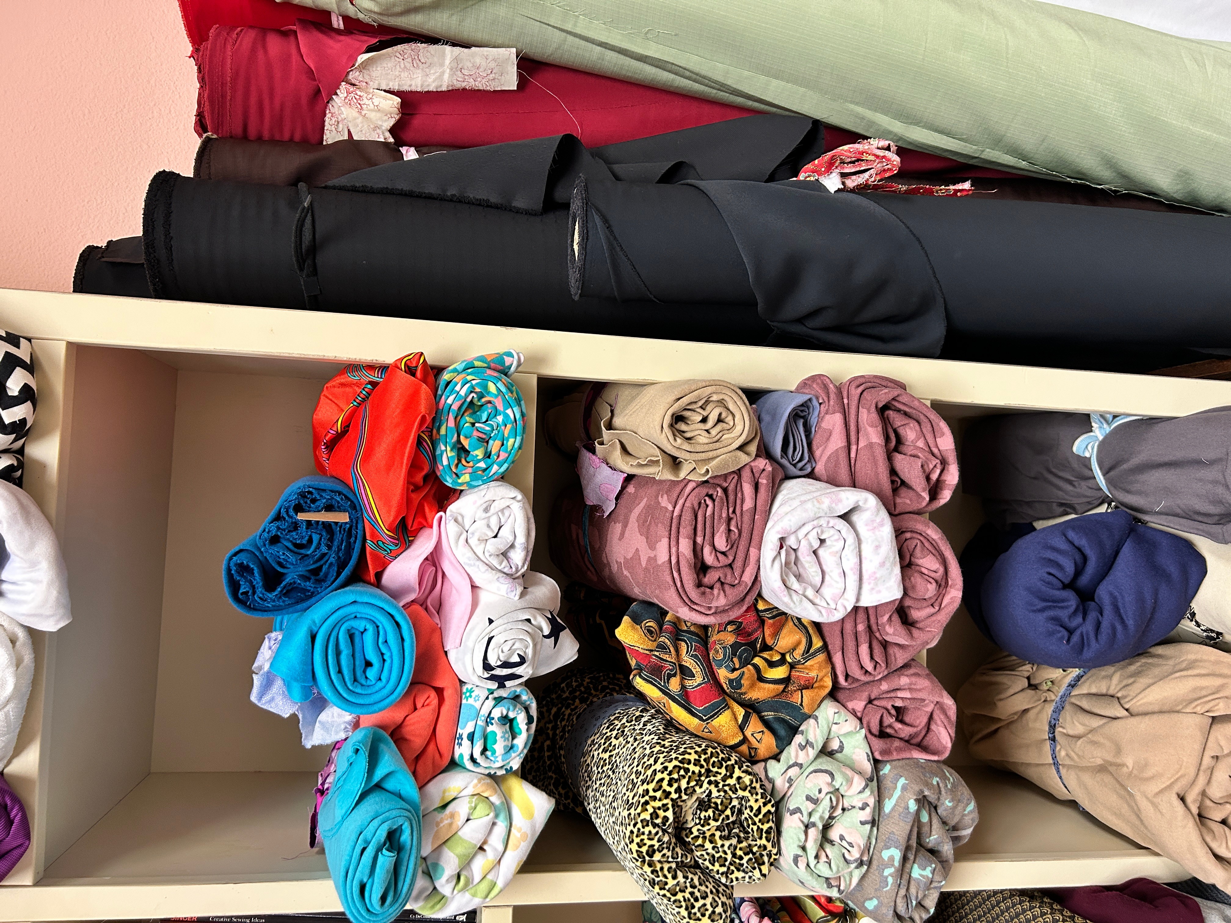 Shelves filled with rolled and folded fabric or clothing items in various colors and patterns.
