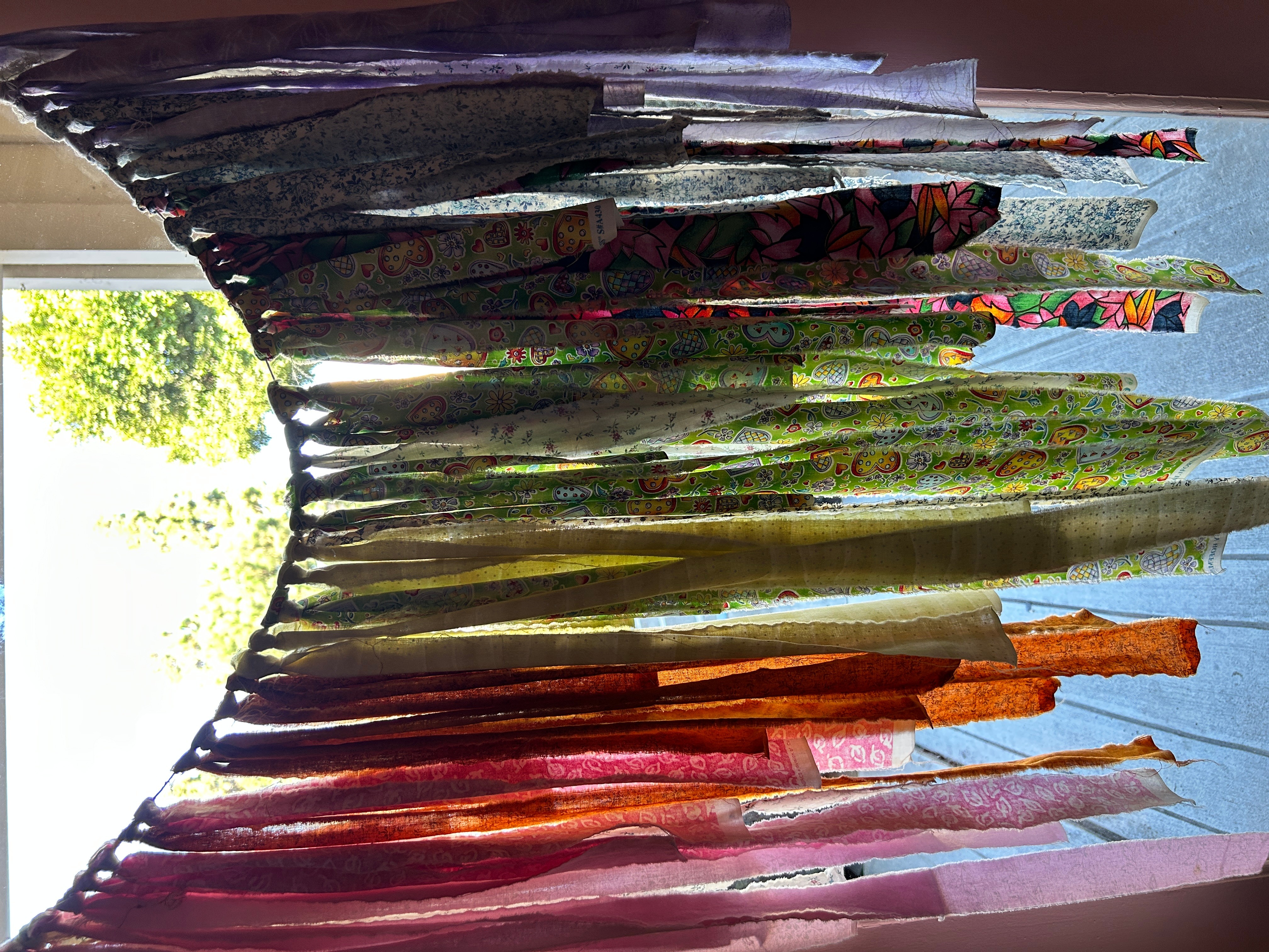 Colorful fabric or curtain hanging vertically with sunlight shining through, creating a bright background.