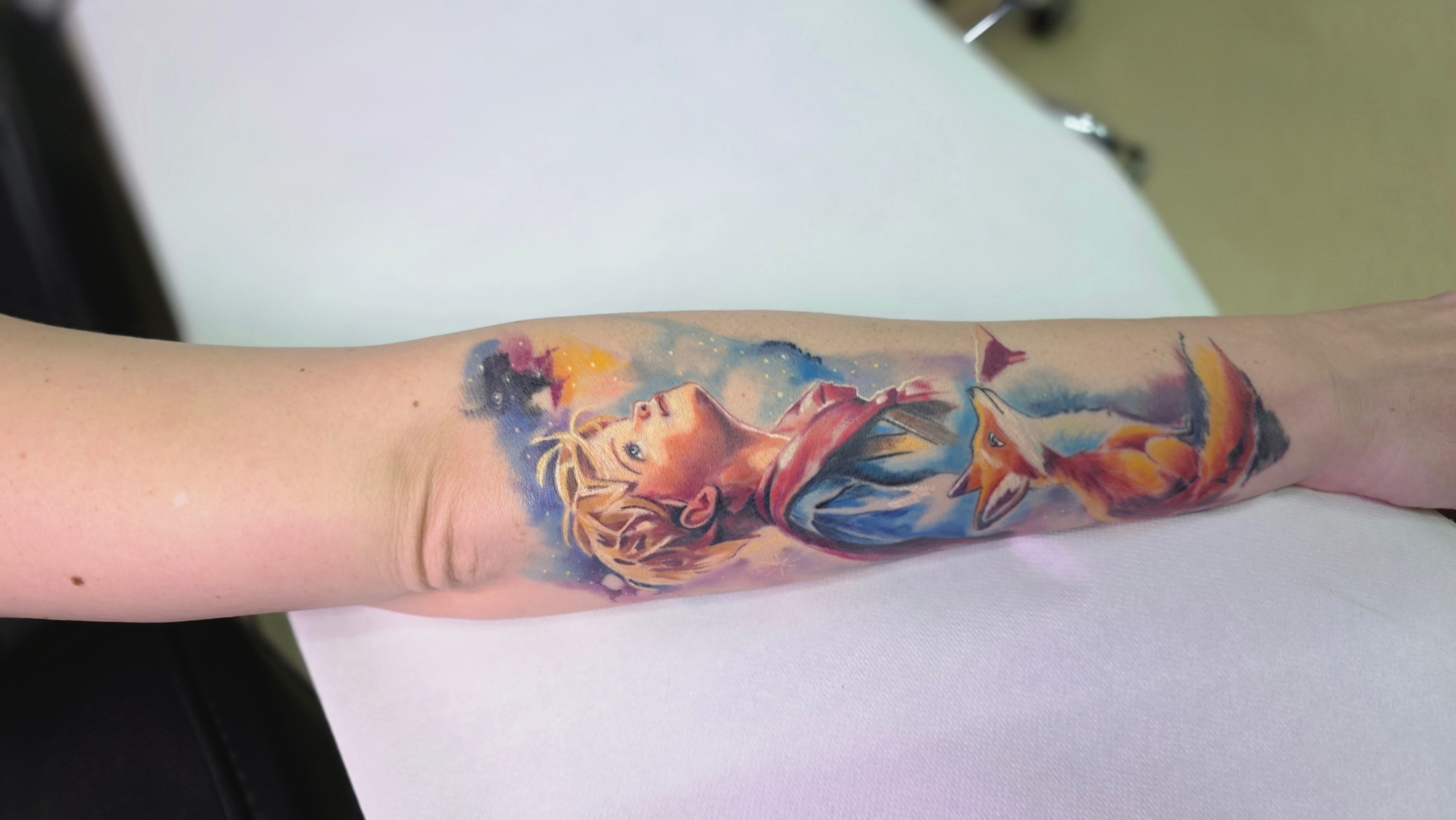 Colorful tattoo of a woman with flowing hair on forearm, with clouds and abstract elements, in vibrant hues.