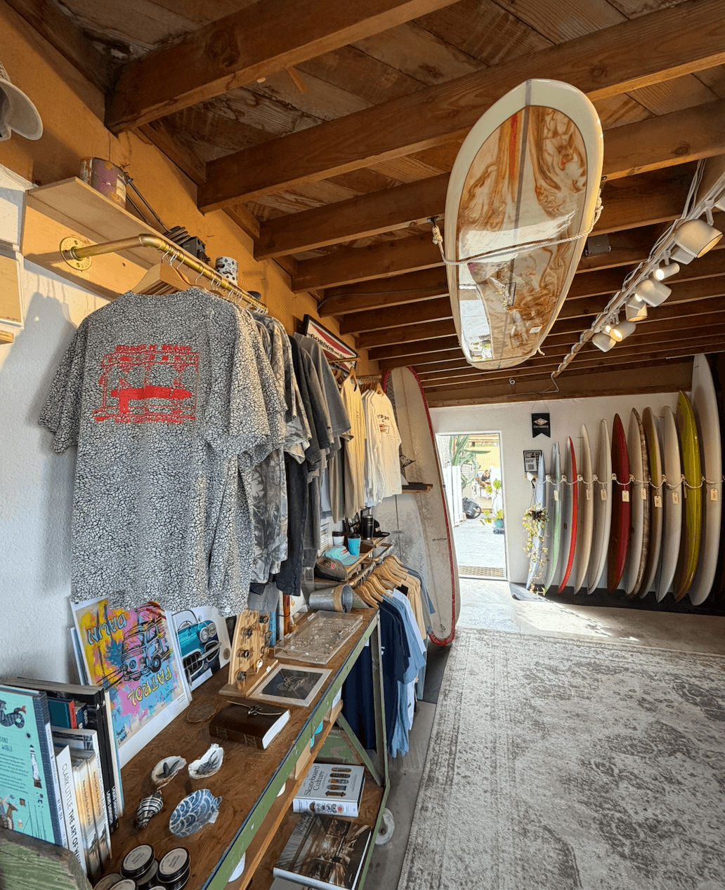 Surfboards stored vertically against a wall, with a wooden ceiling and a window in the background.