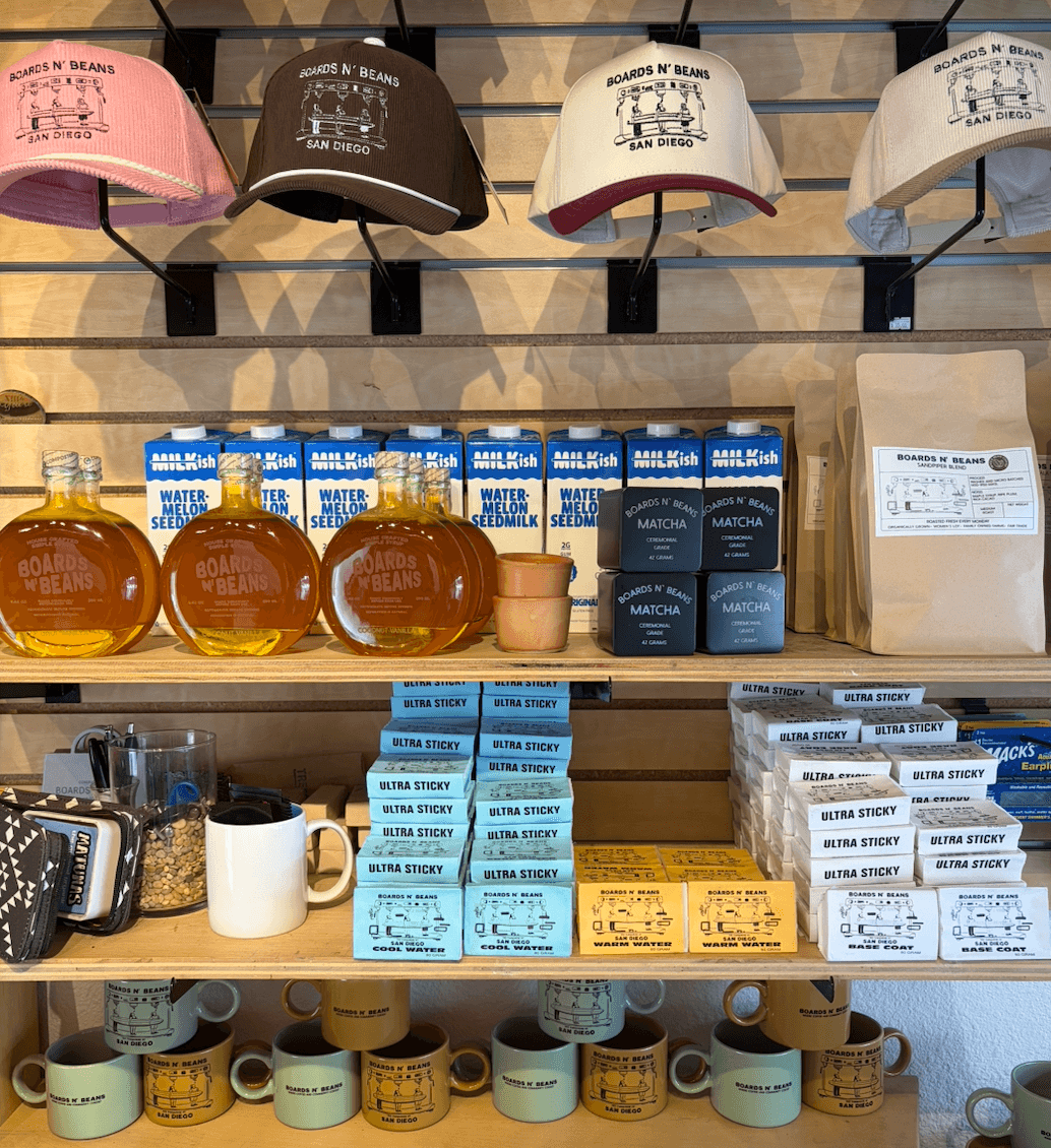 Display of hats, bottled honey, soap, and mugs on shelves in a store.