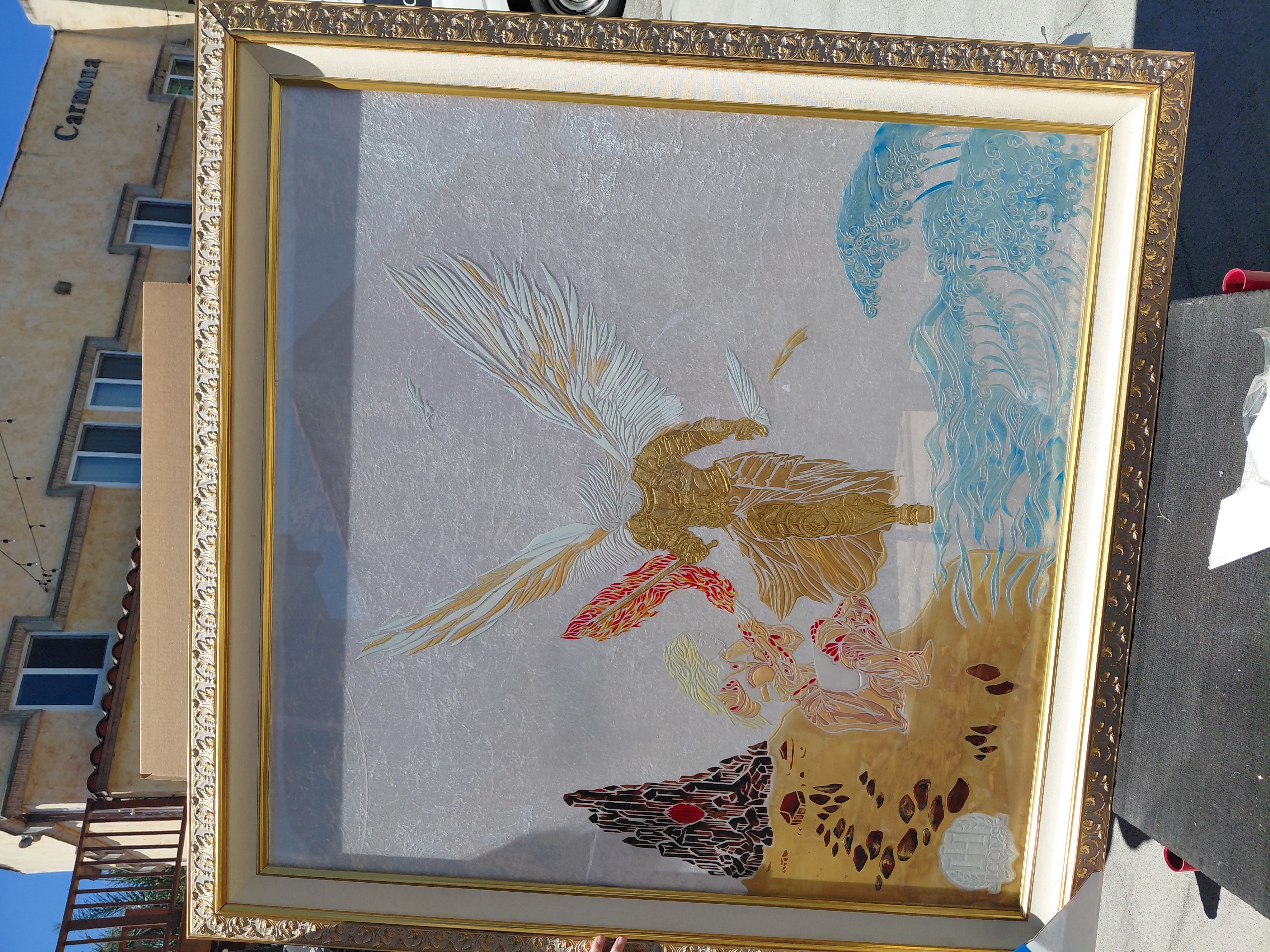 Framed artwork depicting a bird with a long tail, colorful feathers, and a background with blue and yellow elements.