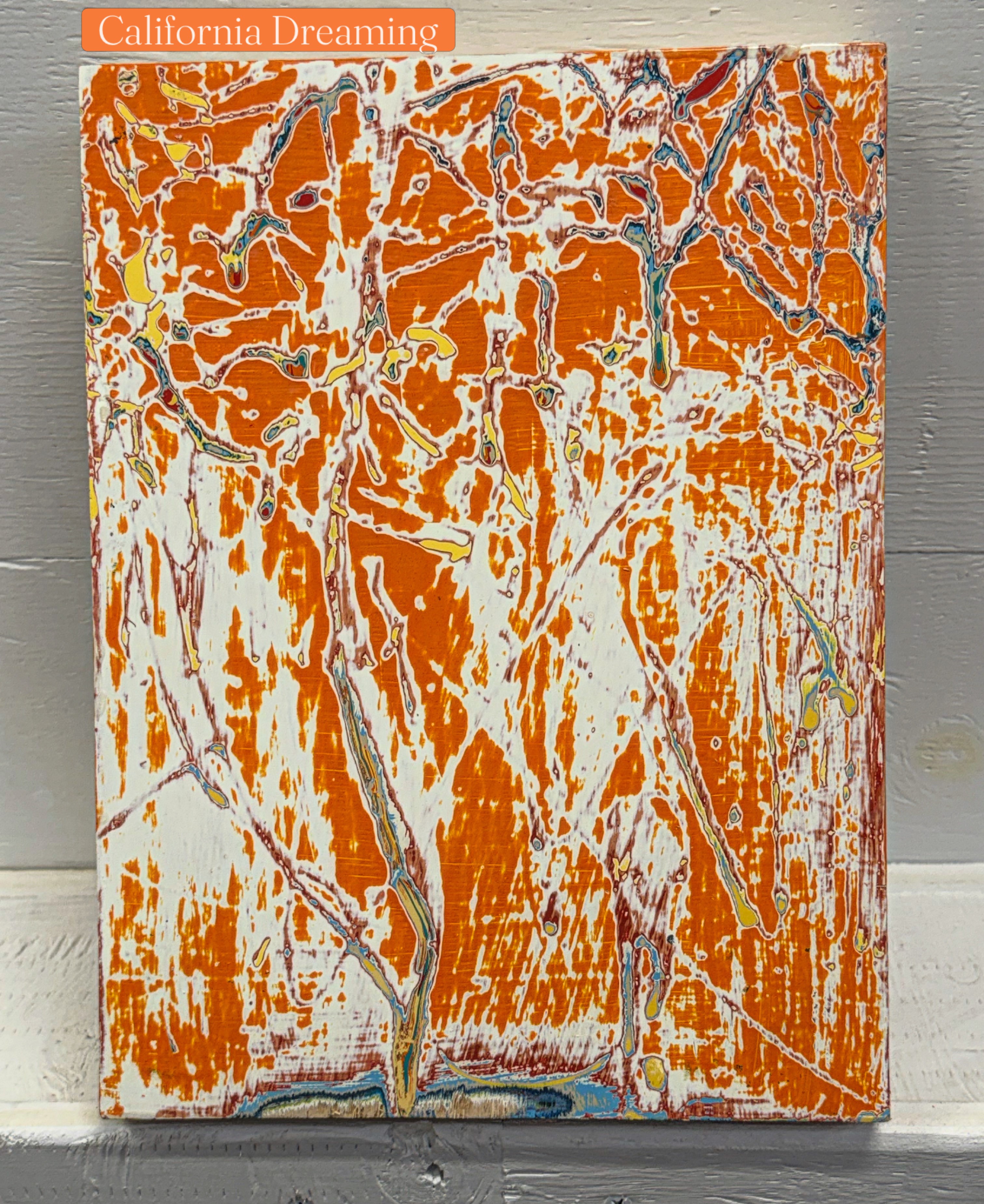Abstract orange, white, and gray marbled pattern on a canvas with a small orange label reading 'California Dreaming' at the top left.