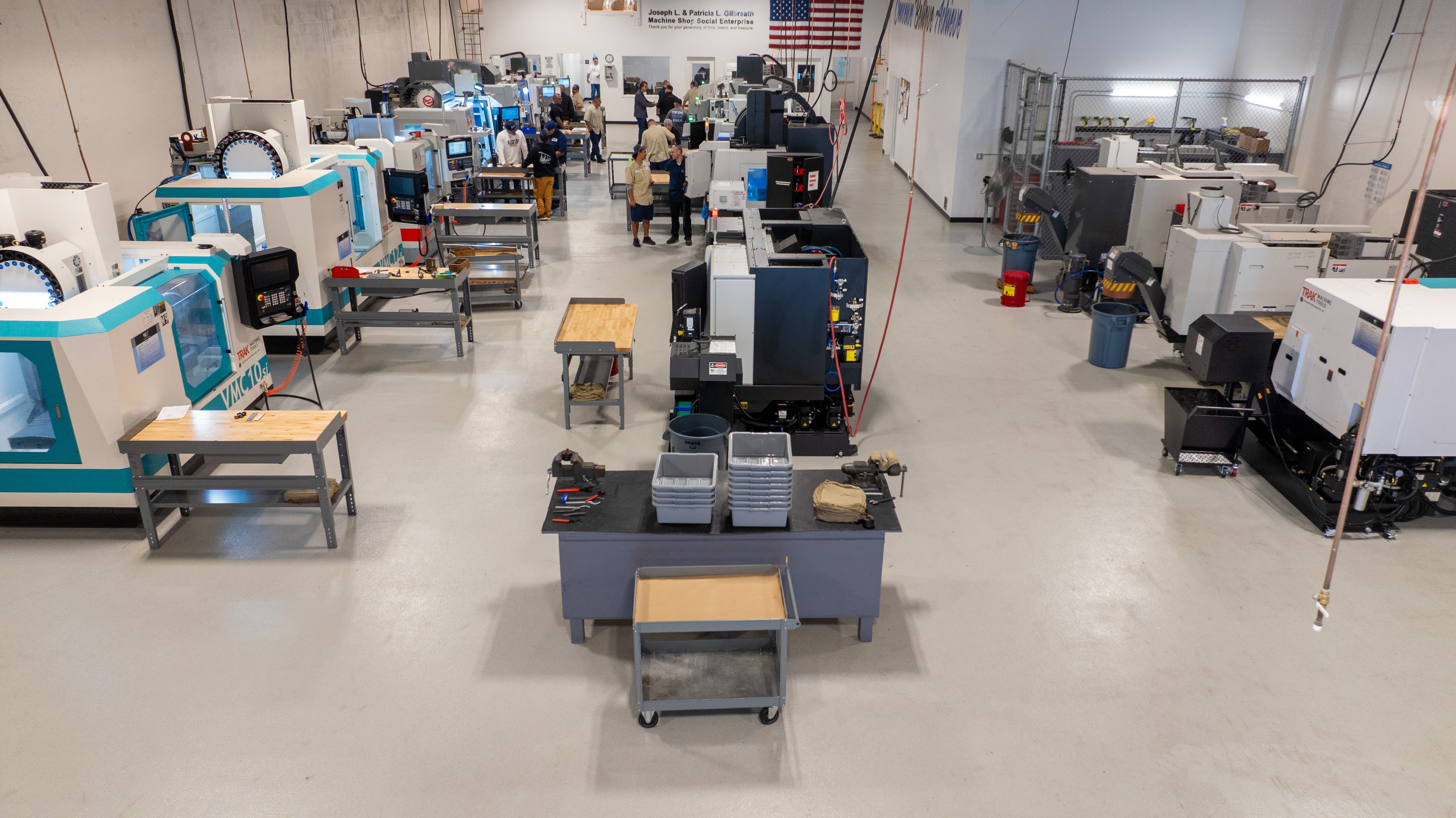 Factory or laboratory with machines, workstations, and people working, viewed from the front, wide-angle shot.