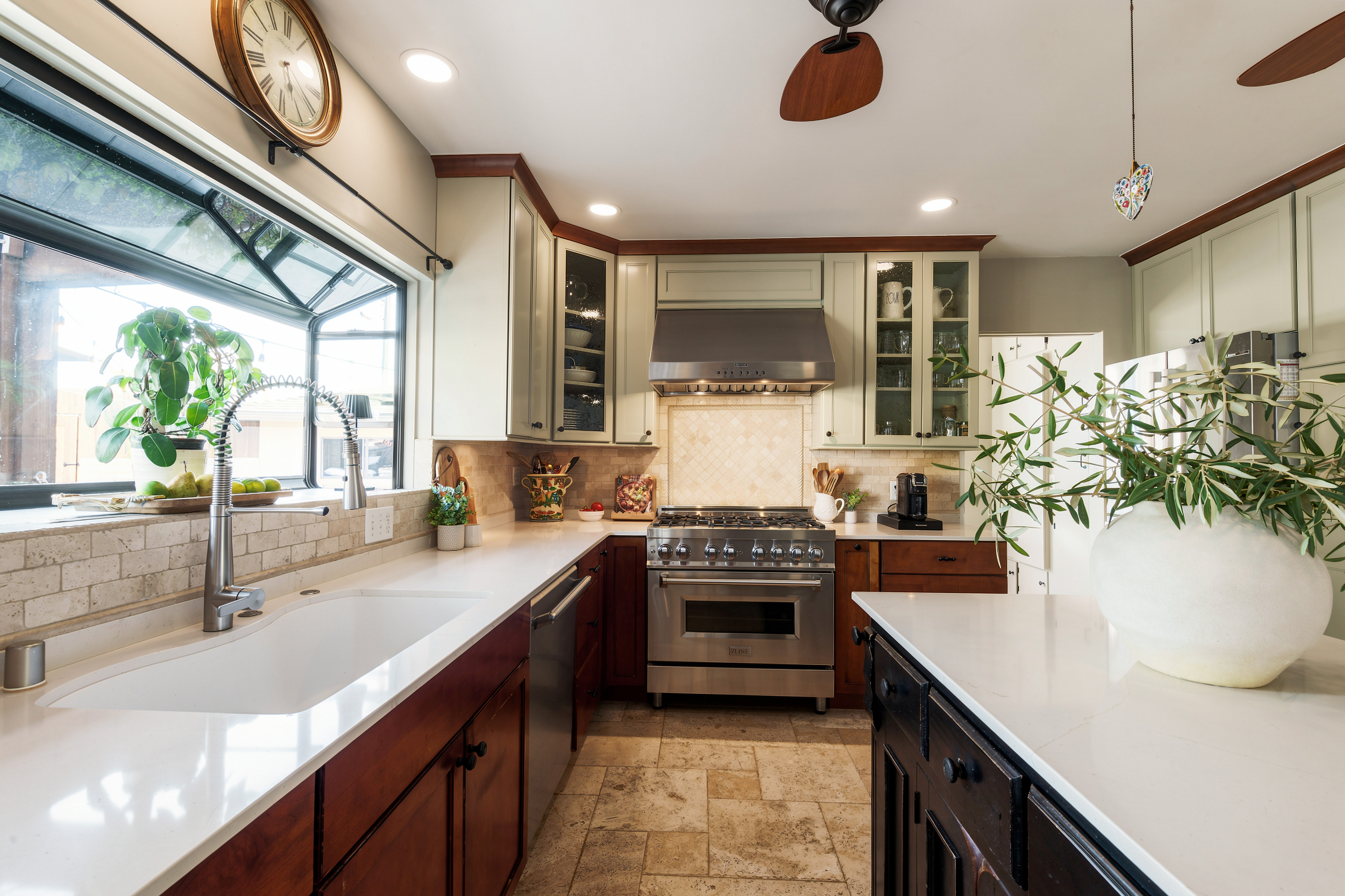 Kitchen with white cabinets, dark lower cabinets, a window with plants, and a stove in the center.