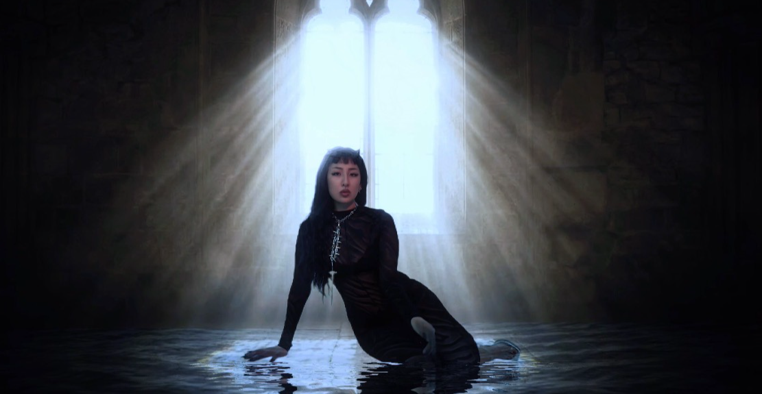Person kneeling in water with light streaming through a window behind, creating a dramatic silhouette.